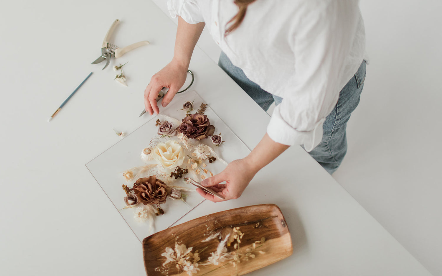 birds-eye view of artist designing with preserved flowers